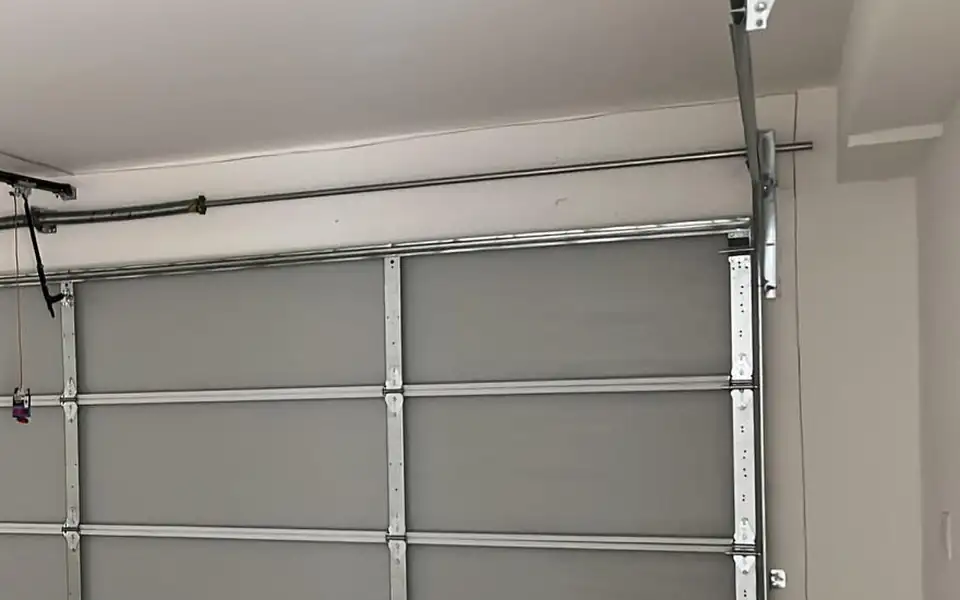 Torsion shaft, cable drum and vertical track at the top corner of a garage door