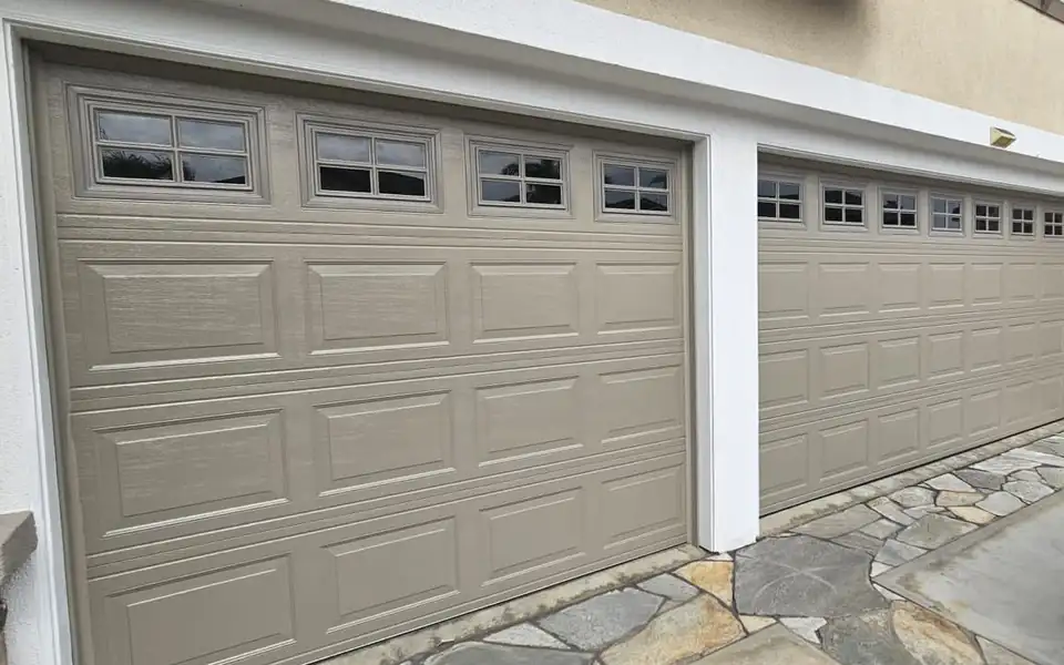Two insulated steel garage doors with window rows on a house
