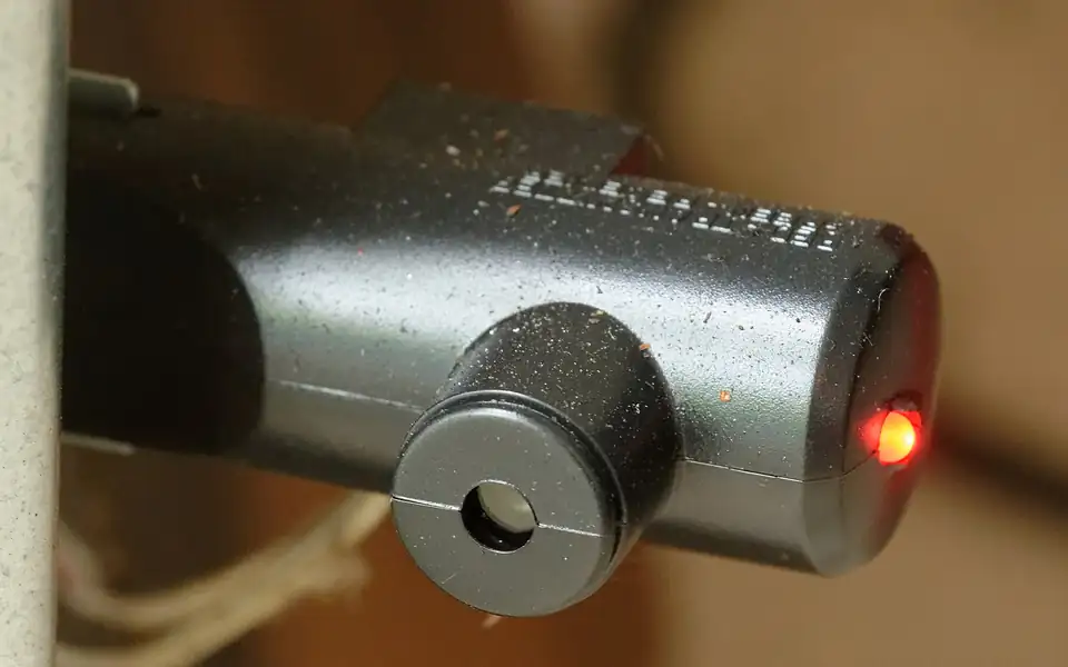 Close-up of a garage door safety sensor with its indicator light on