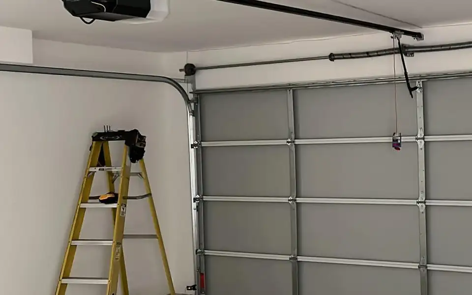 Garage door tracks, rollers and opener rail inside a garage with a ladder