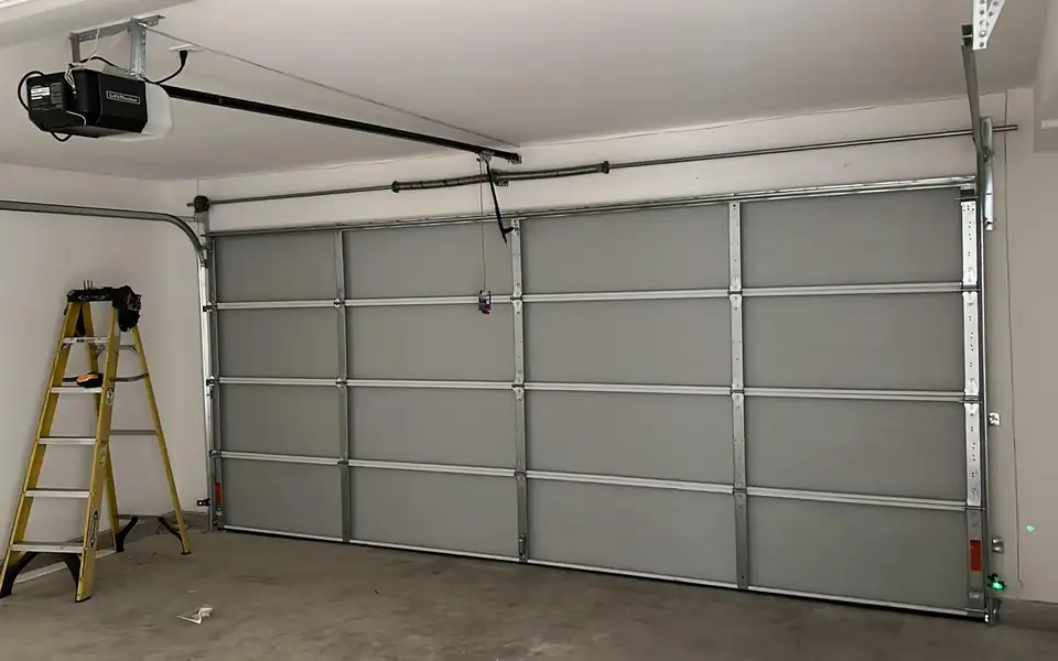 Inside a two-car garage with a gray sectional door, tracks and a ceiling opener
