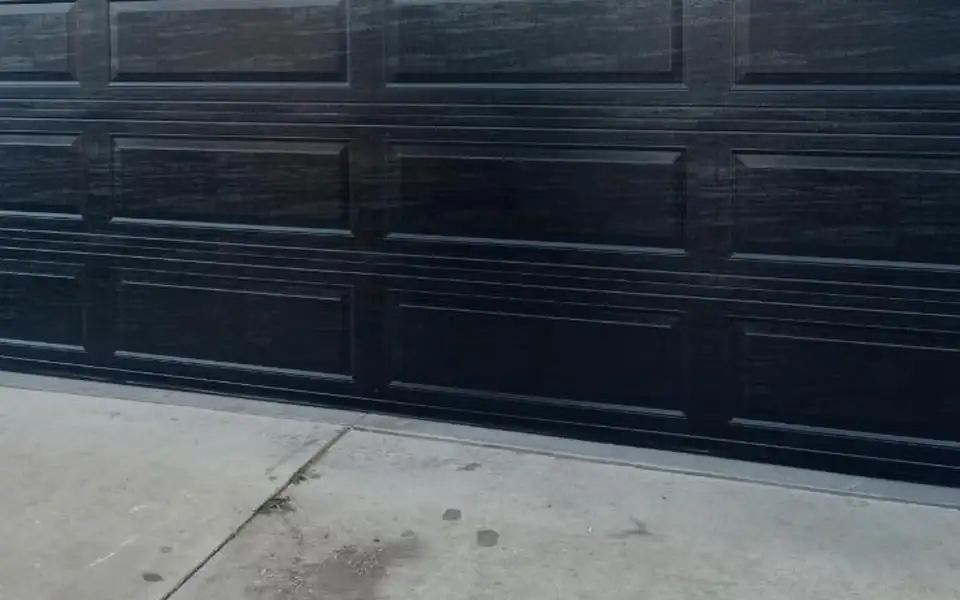 Bottom section of a black garage door where it meets the driveway